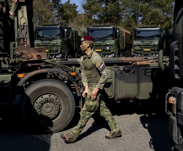 Militair loopt tussen militaire vrachtwagens.