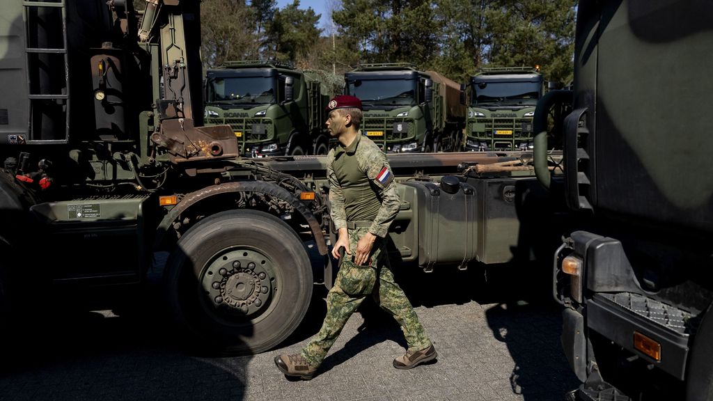 Militair loopt tussen militaire vrachtwagens.