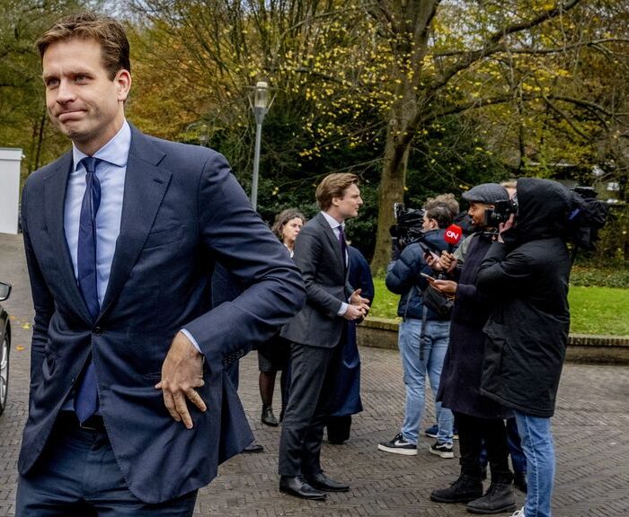 Man arriveert bij gebouw, pers interviewt hem