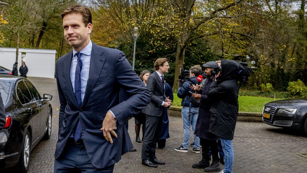 Man arriveert bij gebouw, pers interviewt hem