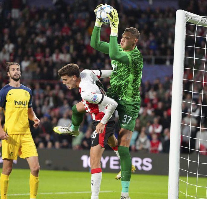 Keeper vangt bal bij voetbalwedstrijd in stadion.