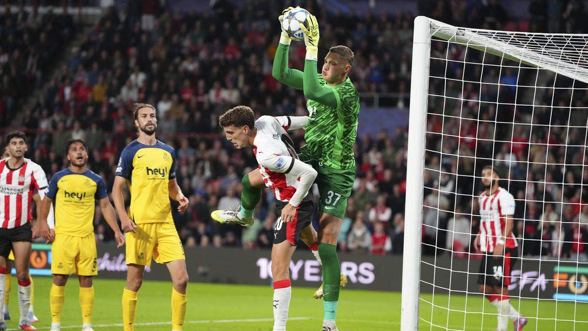 Keeper vangt bal bij voetbalwedstrijd in stadion.