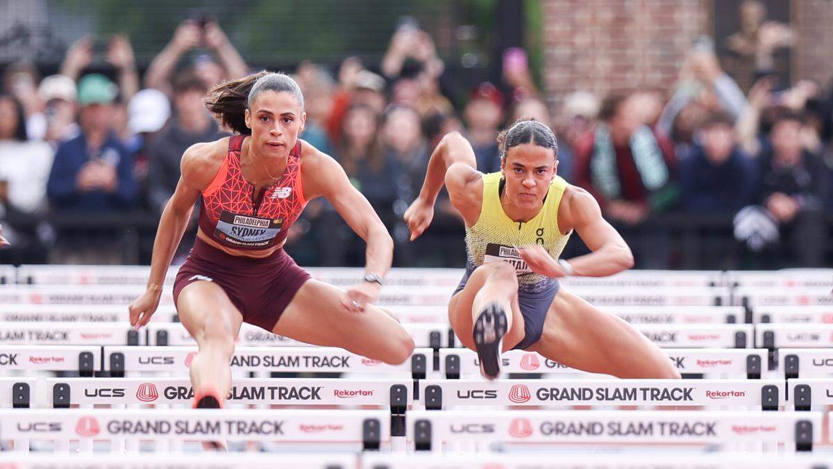 Vrouwen springen over hordes op atletiekbaan.