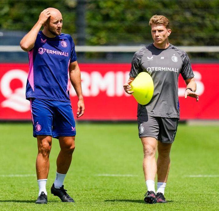Twee mannen bespreken trainingsstrategie op sportveld.