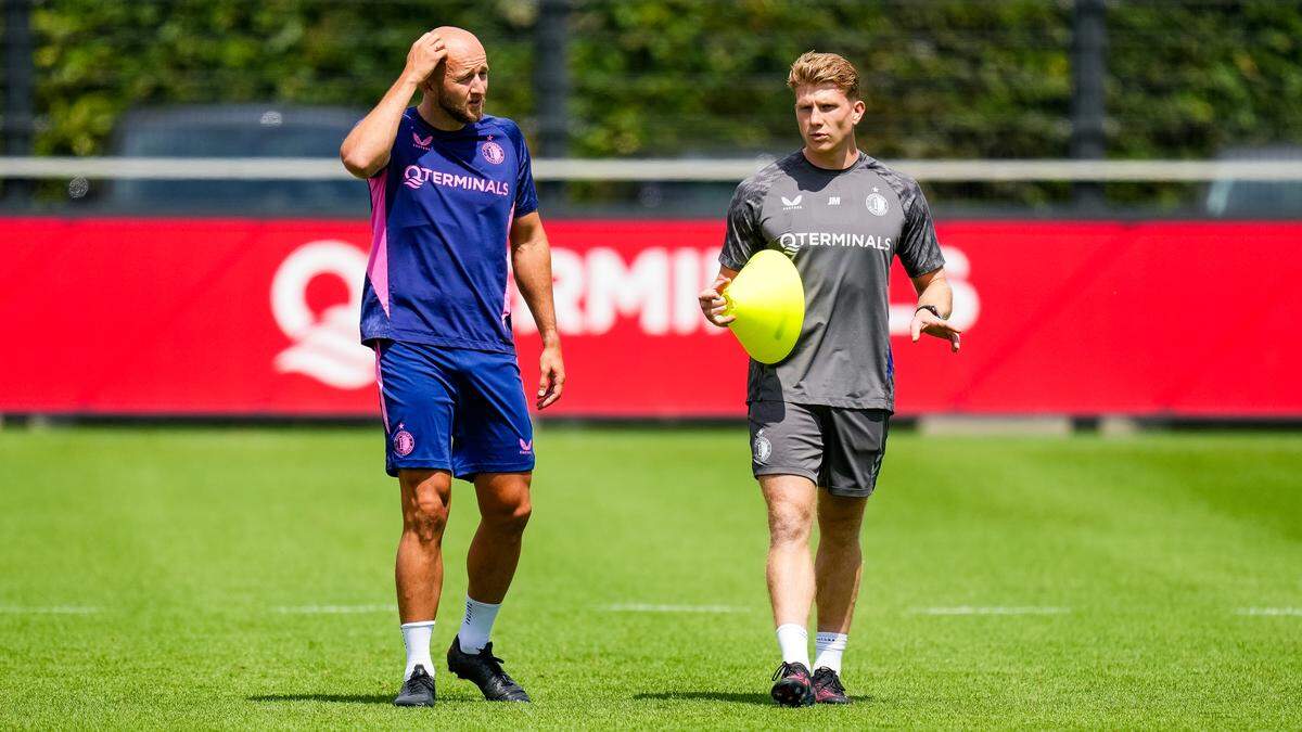 Twee mannen bespreken trainingsstrategie op sportveld.