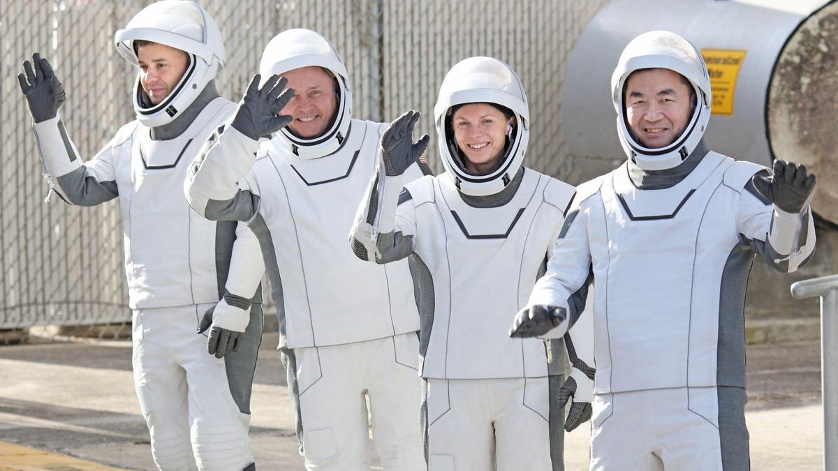 Astronauten in witte pakken zwaaien lachend.