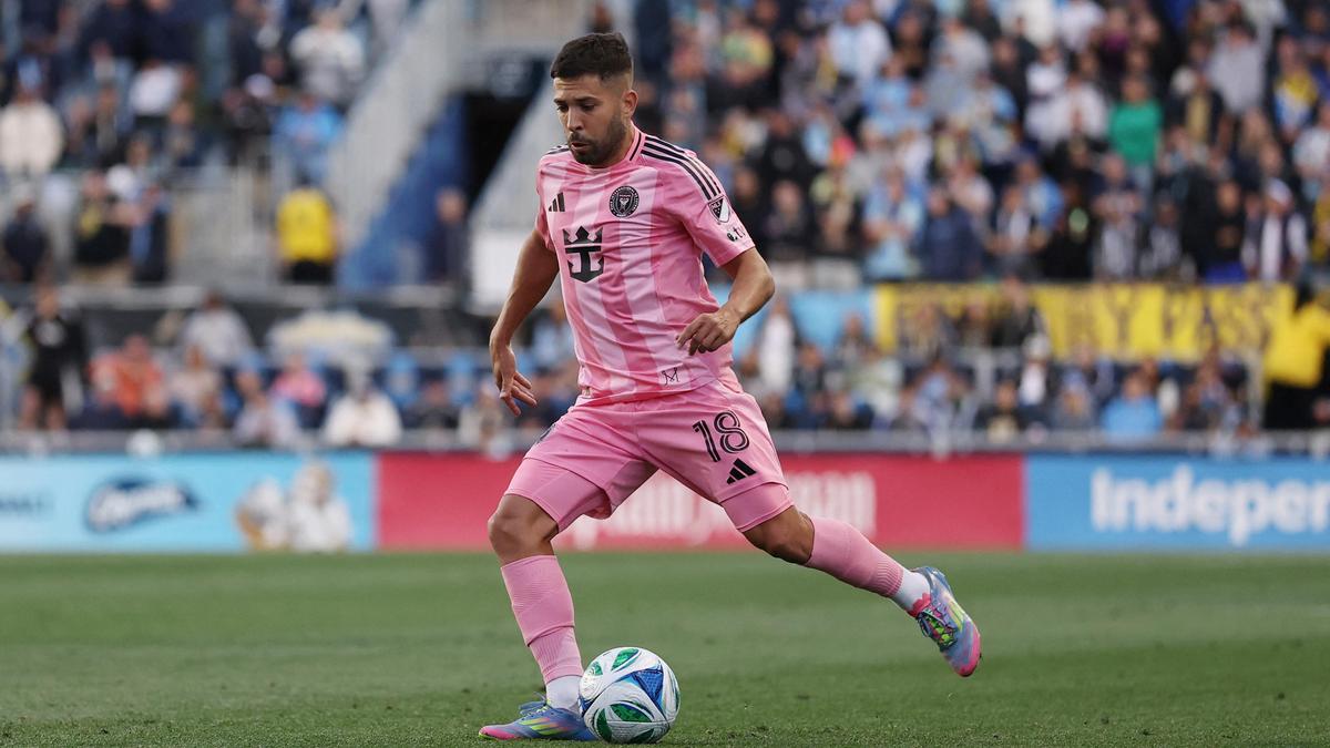 Voetballer in roze tenue met bal op veld