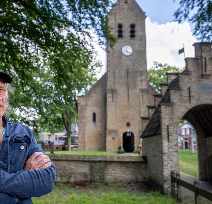 Man bij oude kerk met groene bomen.
